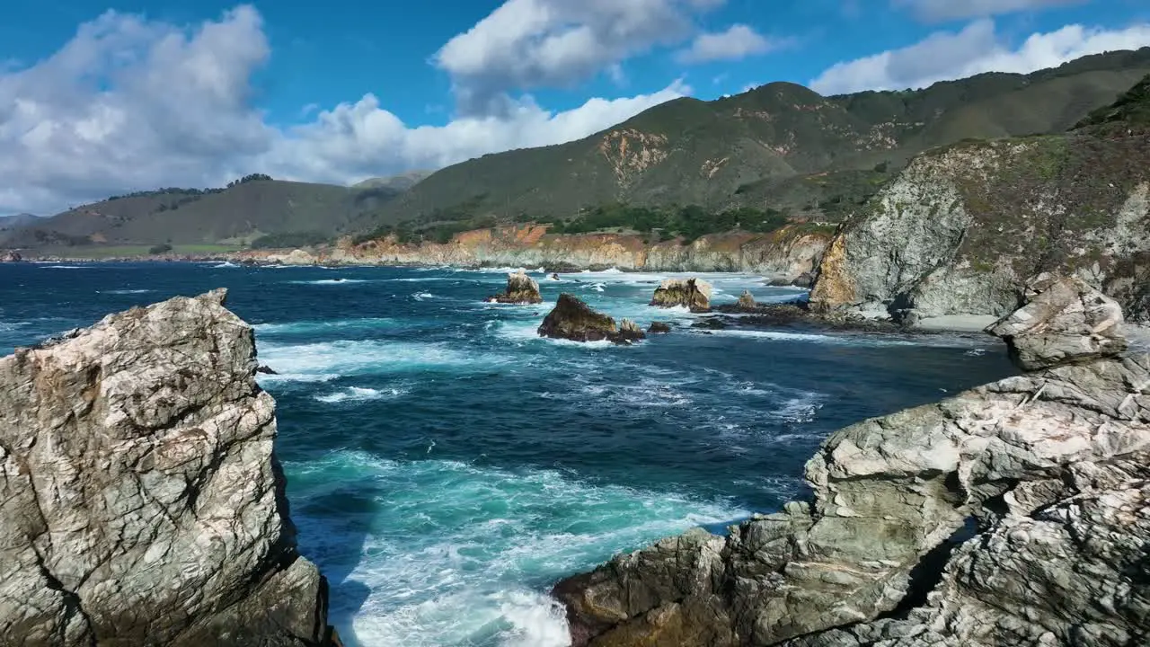 Aerial shot of blue waves crashing on rocks along Big Sur Carmel California