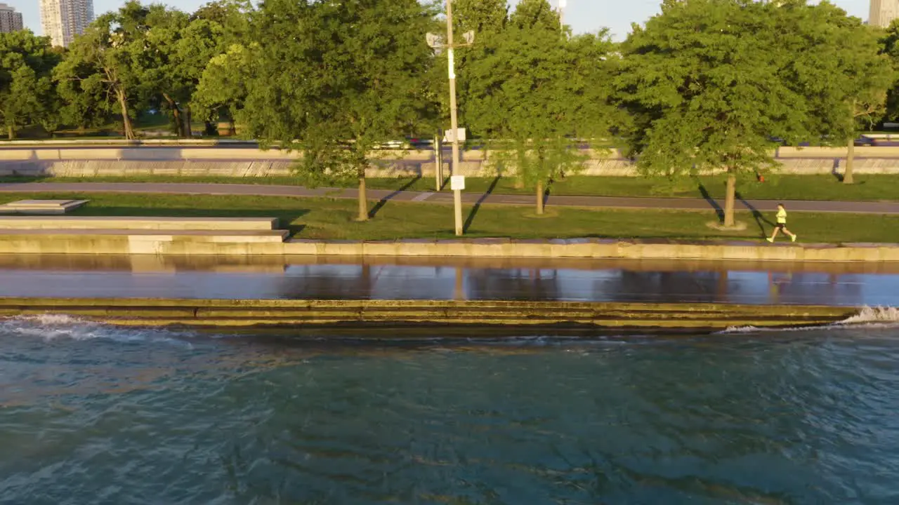 Aerial tracking shot of people exercising along Chicago's Lakeshore Path as waves crash along the path due to high water levels