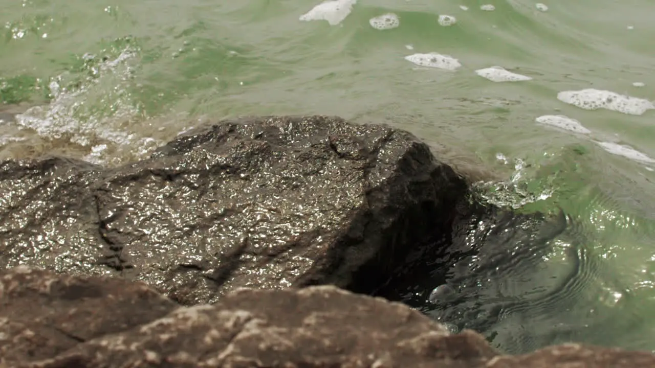 Waves in slow motion hitting the rocky shore and crashing with power