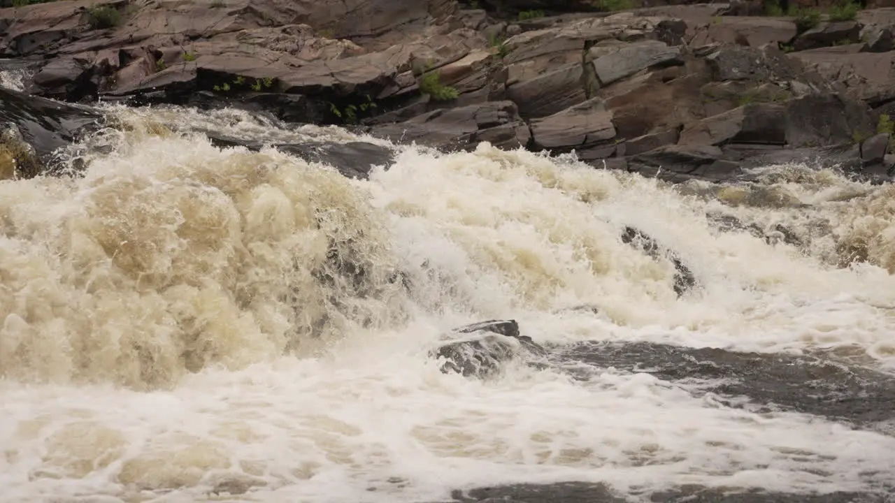 Slow motion white water rapids rushing down a river in a violent force