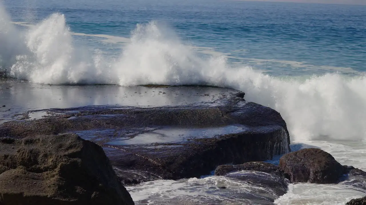 Ocean wave exploding onto rocks and washing over