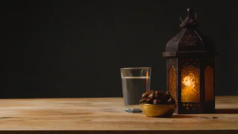 Stationary Shot of Lantern Water and Dates On a Table for Ramadan