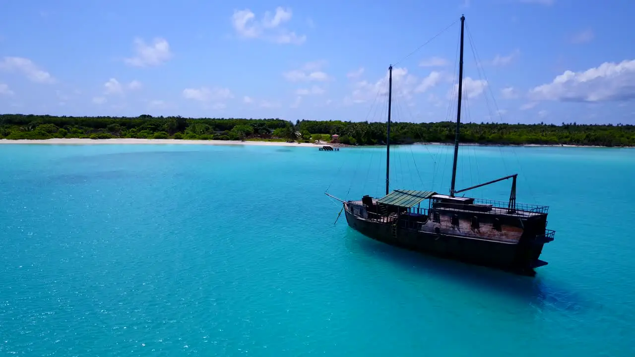 a touristic boat anchored at the turquoise waters of a tropical island drone footage