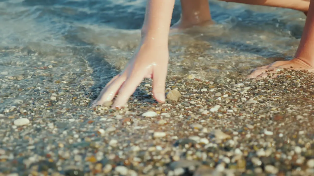 A Woman's Hand Is Looking For Something In Shallow Pebbles On The Edge Of The Sea 4k Video