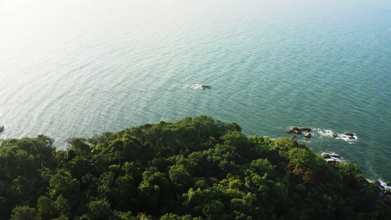 Establishing shot top aerial view of a tradicional wooden fishing boat in the emerald color brazilian ocean during sunset