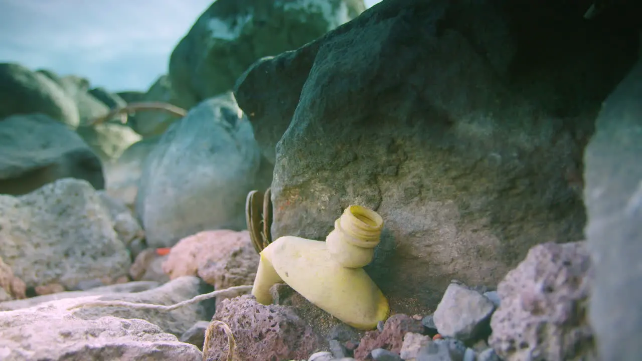 An old plastic bottle lies trapped between a rock and a hard place