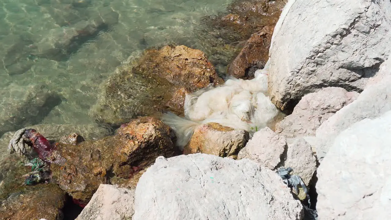 Plastic and trash laying on the rocky shore of the Mediterranean sea in Mallorca