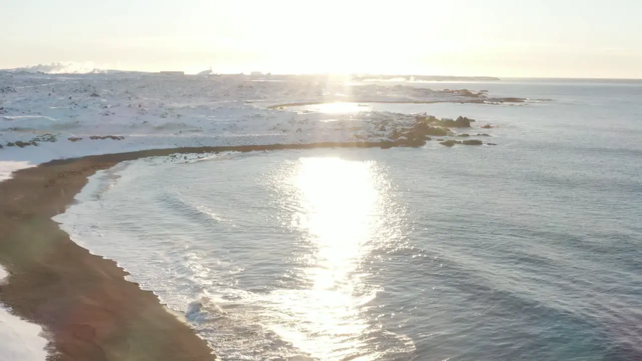 Bright midday sun shines over Iceland coast covered in snow at Sandvik