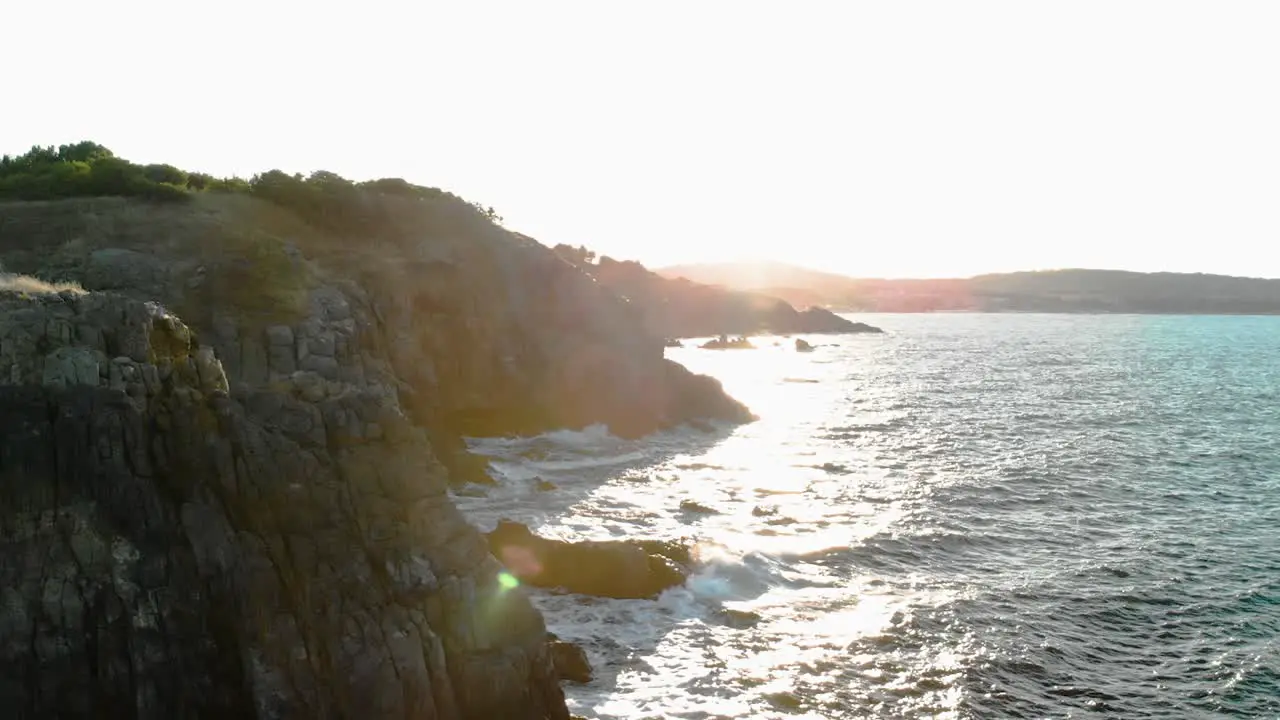 Aerial pan shot of sun rays illuminate through big seashore cliffs in sunset Bulgaria