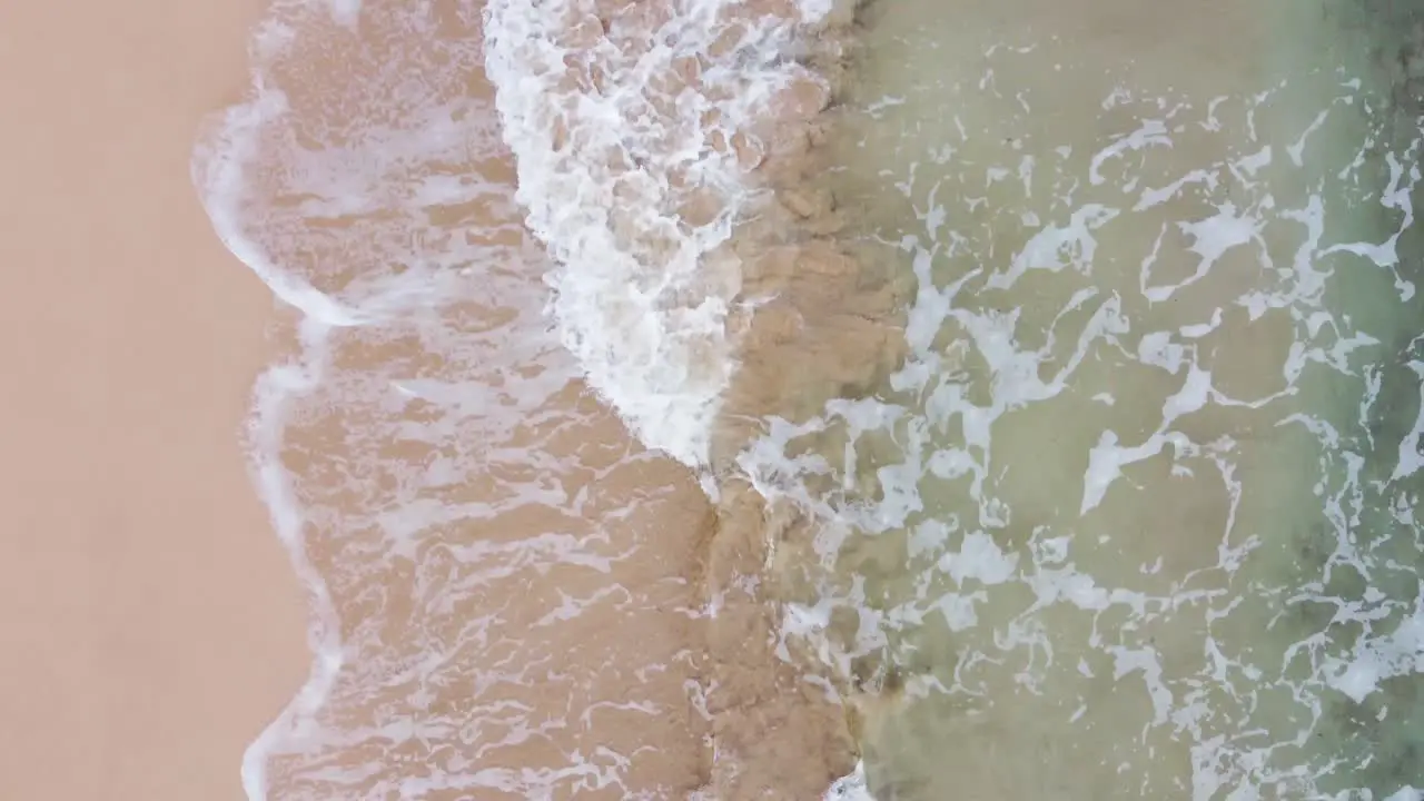 Fast moving Aerial top view over clear Turquoise ocean water foaming at the shore washing the golden sand of the beach Idyllic summer vacation on Hawaii island