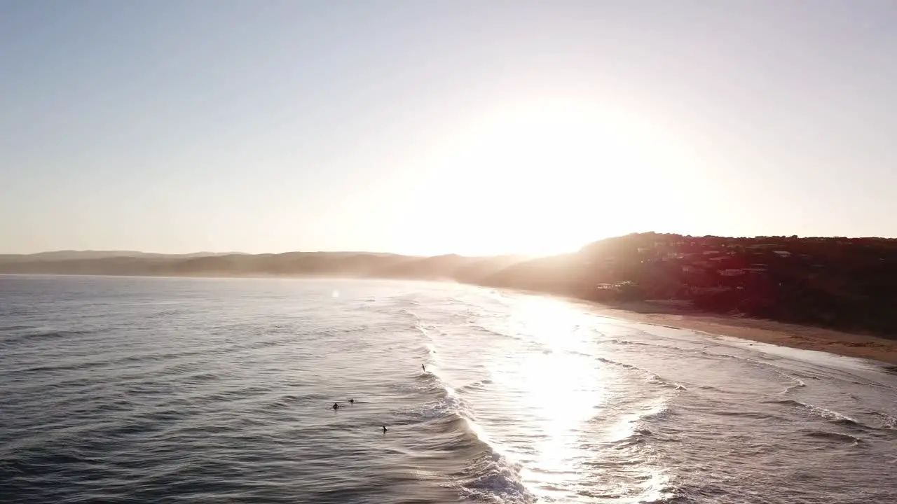 Drone aerial during sunset at beach with surfers catching waves