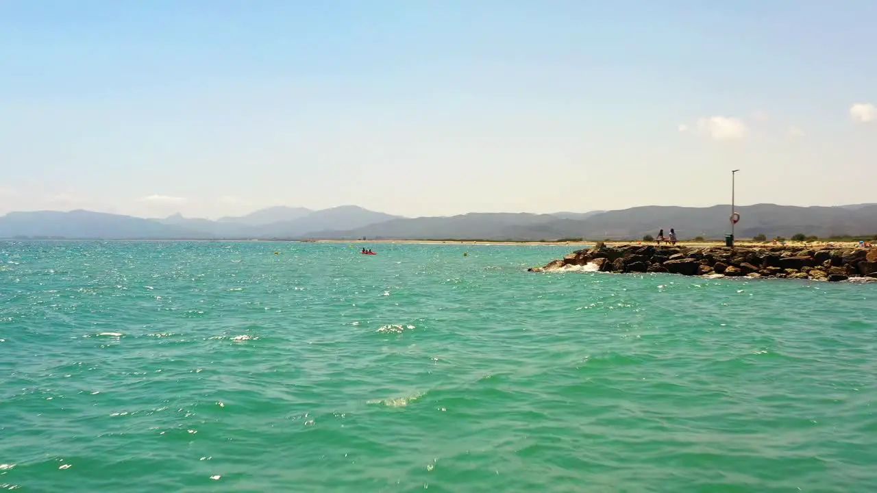 Low drone shot of turquoise water in the Mediterranean coast of Castellon with mountains on the horizon