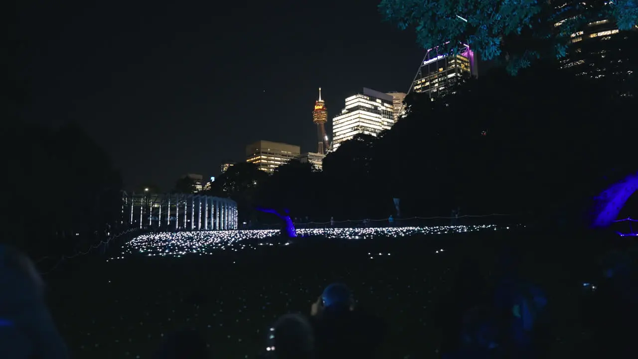 Hundreds of White Flashing Lights on the Ground with People Looking on at Sydney Botanic Gardens for Vivid in Slow Motion