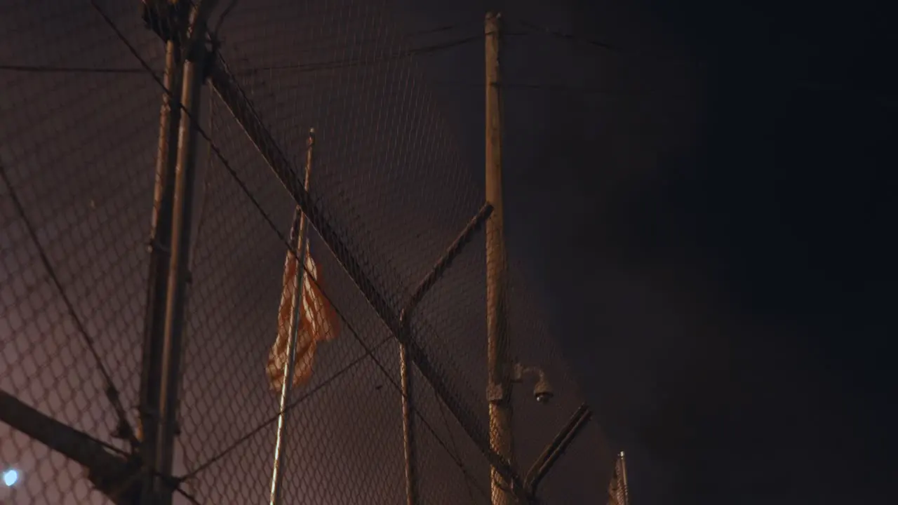 American Flag Blowing Behind a Fence Surrounded by Smoke at Night Time