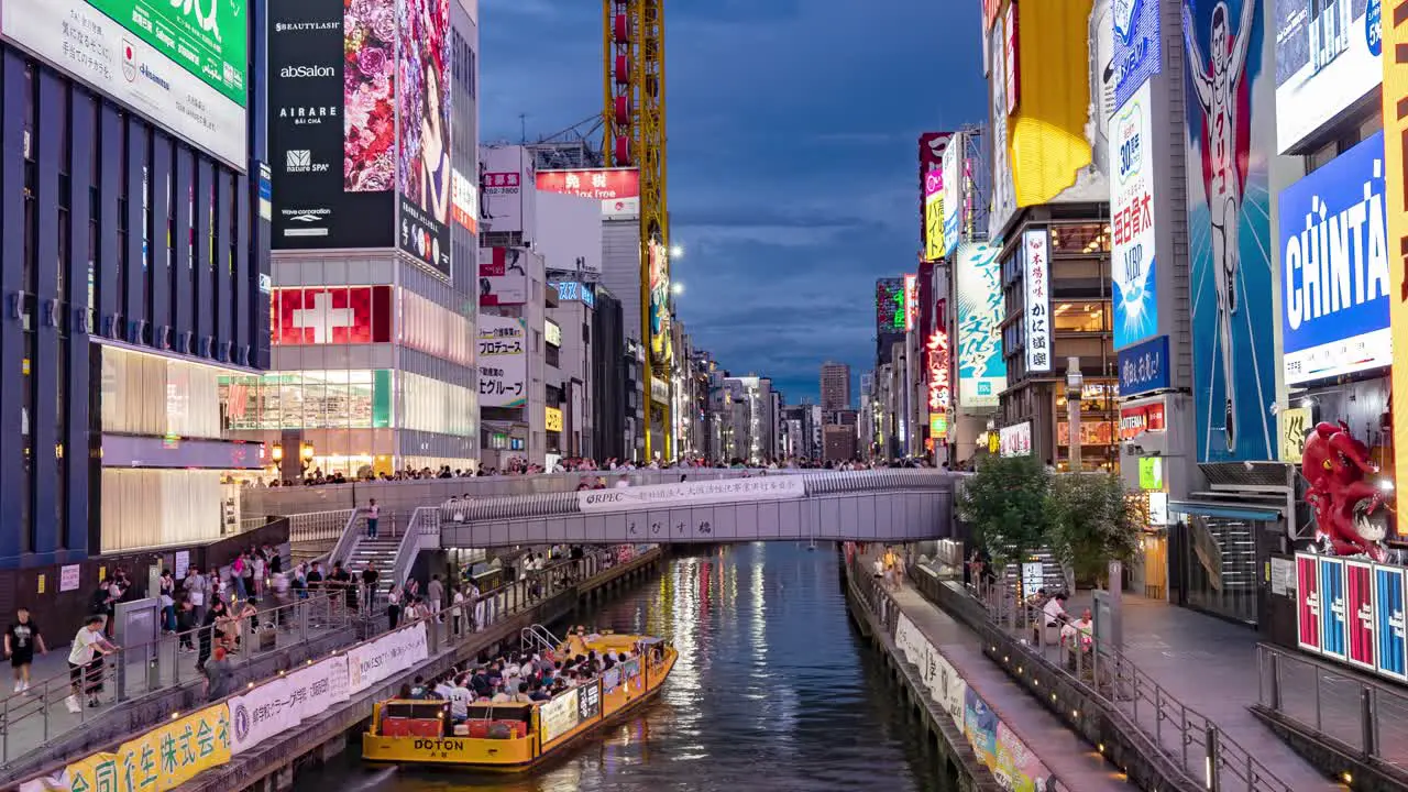 Night Time-Lapse Of Boats passing people and Illuminated signboards at Ebisu Bridge Dotonbori Canal Namba Osaka Japan