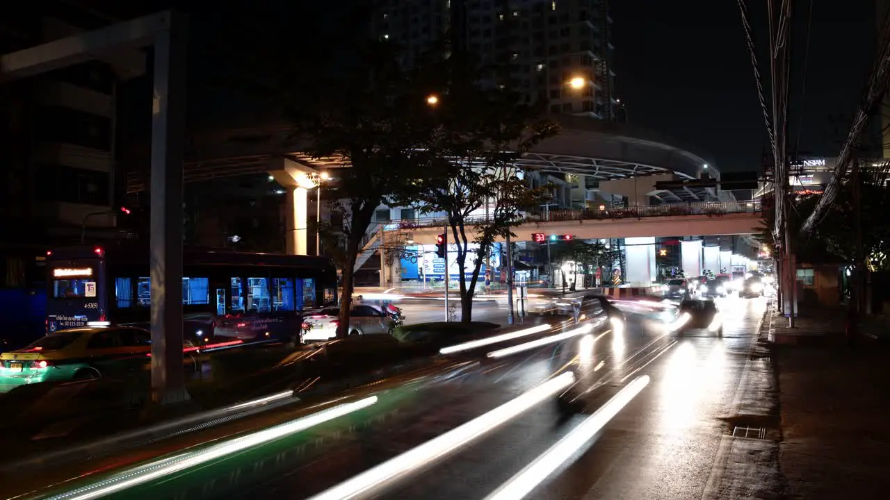 A nighttime time lapse shot of cars whizzing by the camera at high speed in the streets of Bangkok Thailand