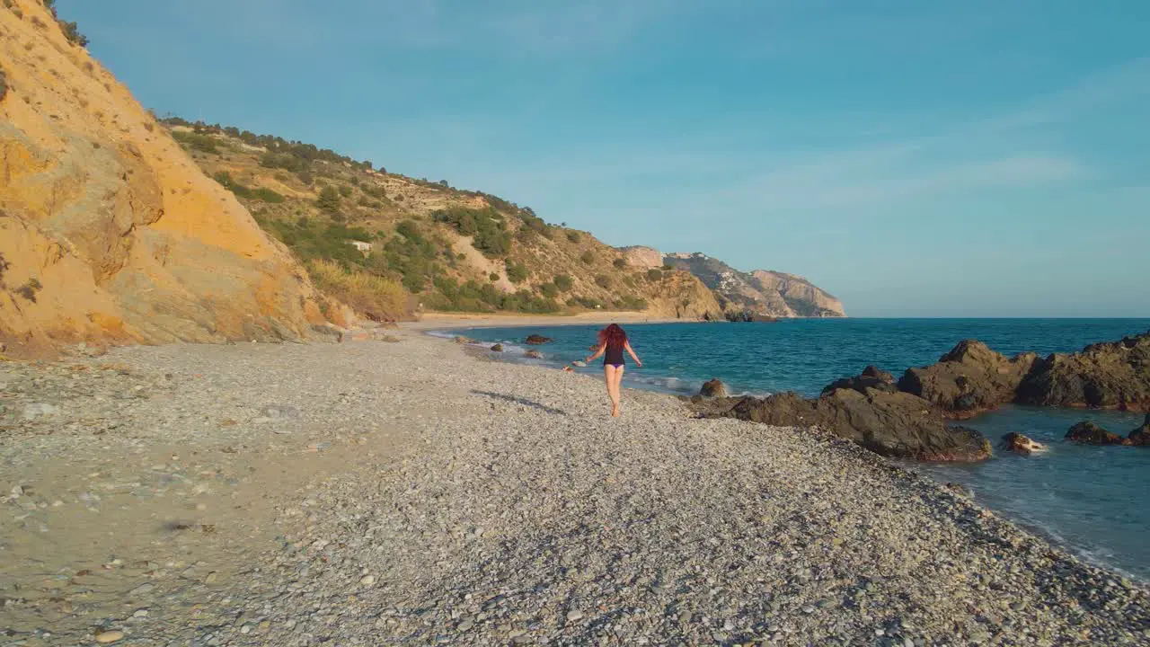 Woman walking at the beach drone moving backwards