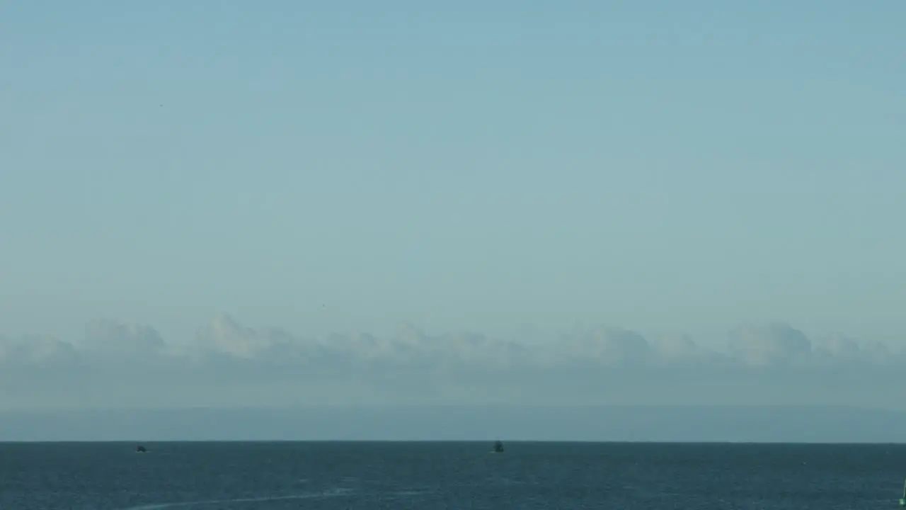 Timelapse of Two Fishing Boats Heading Out to Sea at Sunrise from Swansea UK with Devon Coastline in Distance 4K