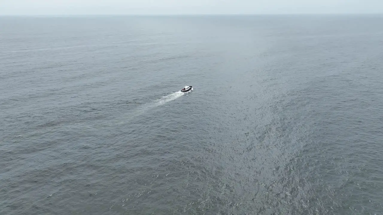 Aerial panning shot of a boat sailing over the sea in the pacific ocean with calm waves on a sunny day