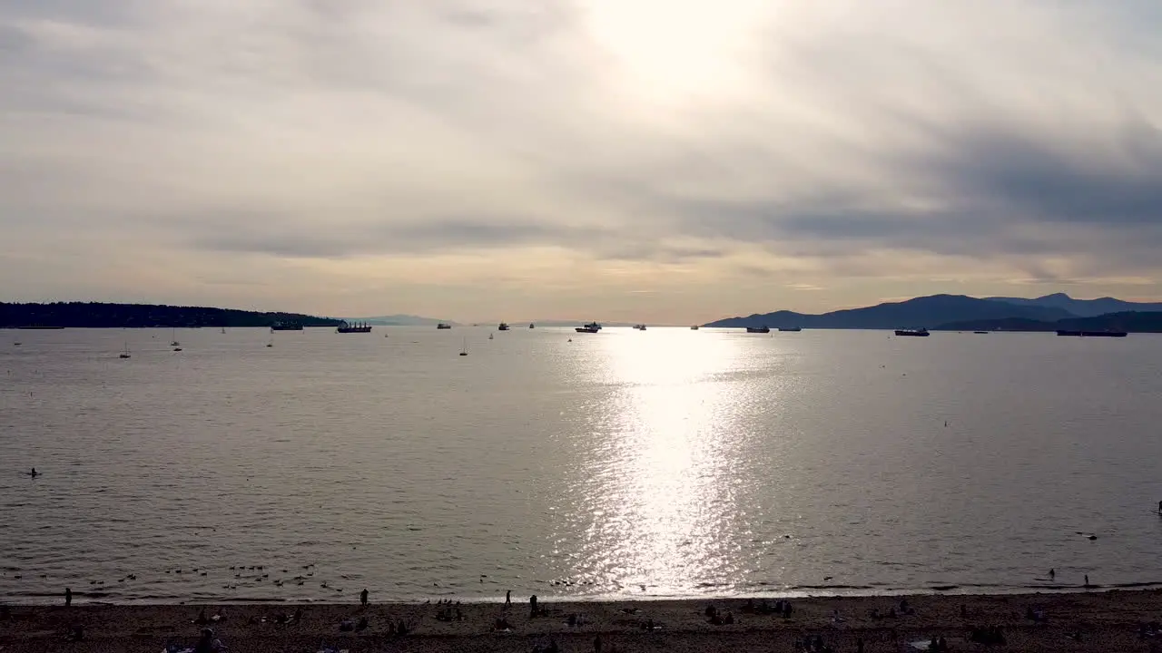 Summer sunset aerial fly over residential private beach at commercial industrial harbor with freightors barges cargo boats line up for iport export trade and recreational vessels parked 2-2