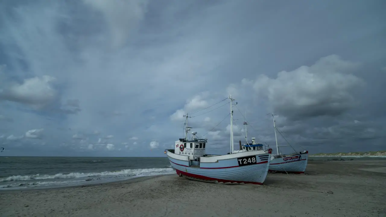 Timelapse of clouds moving over two fisherman boats on a beach