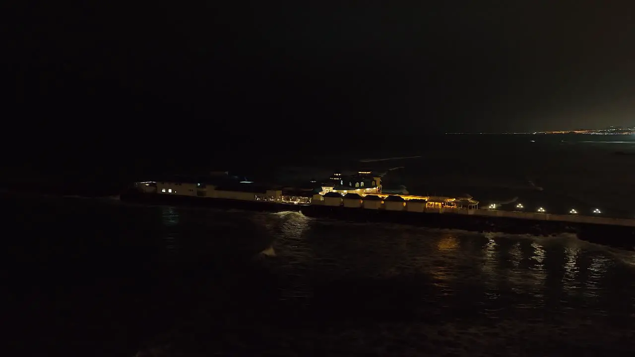 Aerial orbits Rosa Nautica Restaurant on Lima jetty in black of night