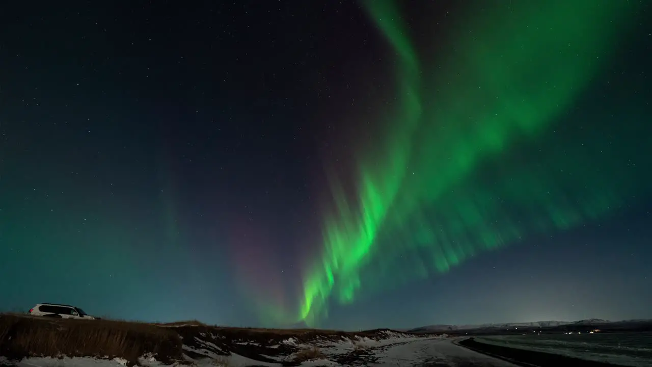 Time lapse shot of flickering green and purple lights at sky over snowy Iceland in winter wide shot