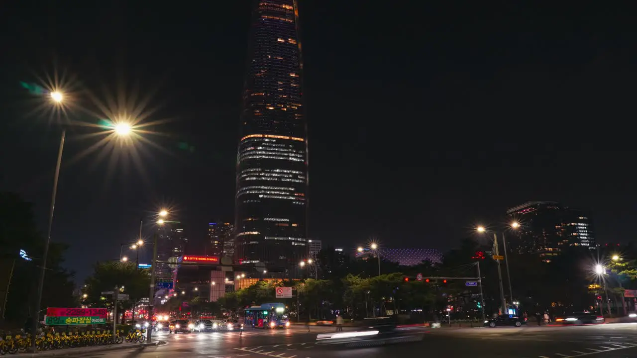 Lotte World Tower at night with busy street traffic on roads intersection in Seoul city downtown timelapse tilt up