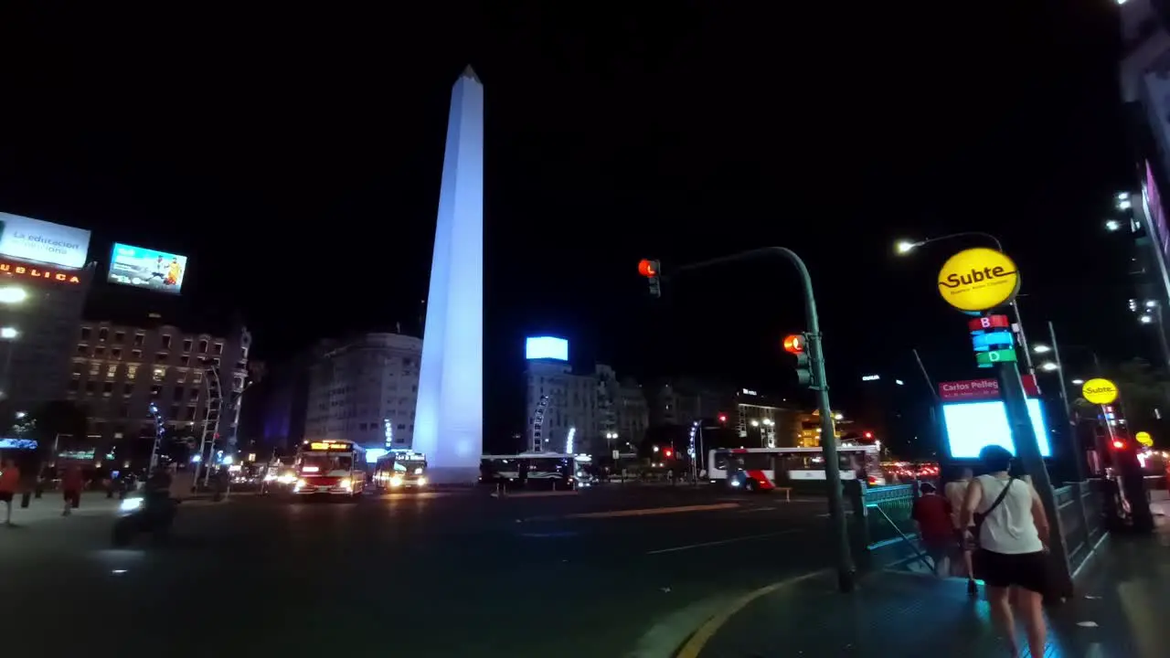 POV night view of the obelisk in Buenos Aires city with traffic jam and people entering subway