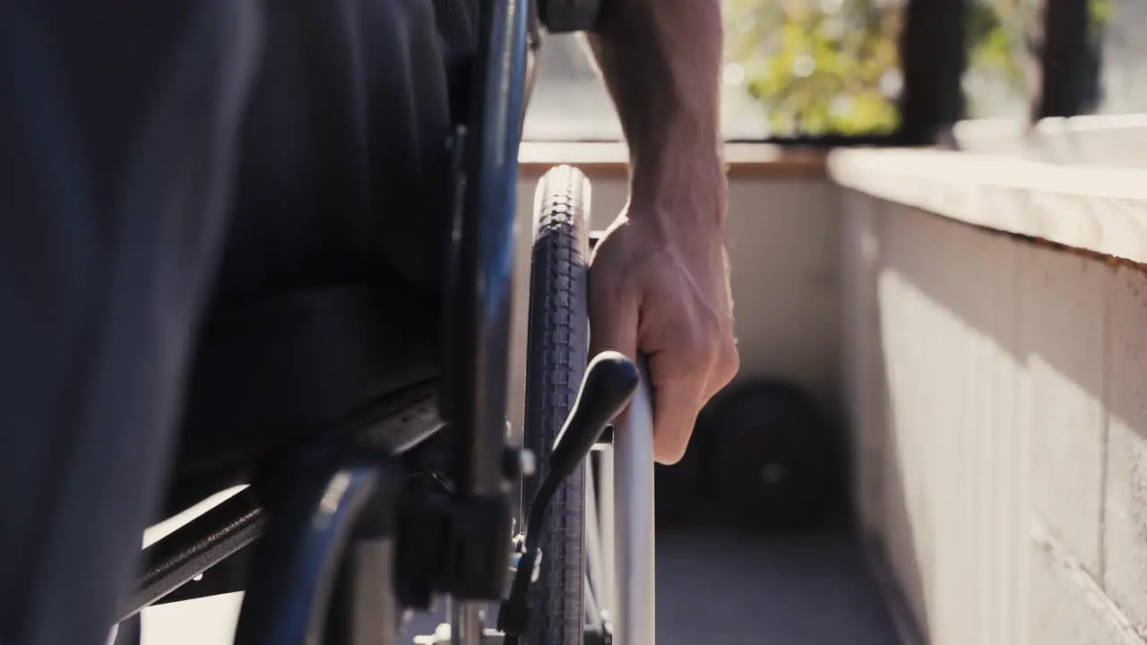 Close Up Of Male Hand On Wheel Of Wheelchair