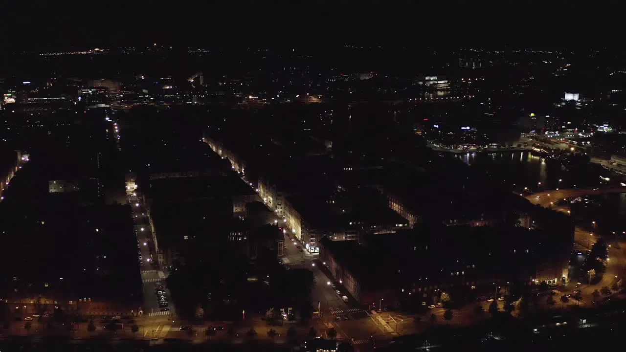 Aerial tracking drone shot panning over buildings and streets in the Kruununhaka cityscape revealing the Helsinki cathedral in the downtown full of lights on a clear night in Uusimaa Finland