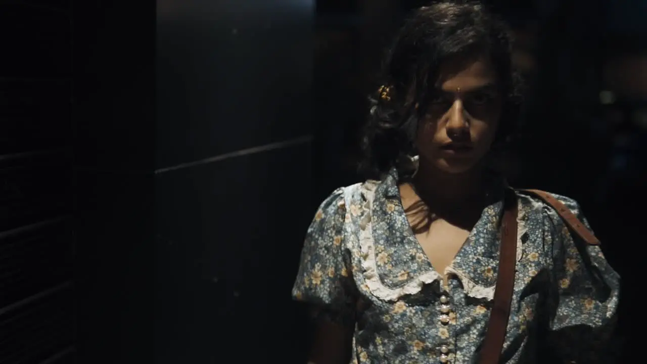 A beautiful woman wearing a bindi on her face in a nighttime environment with vehicles running in the background