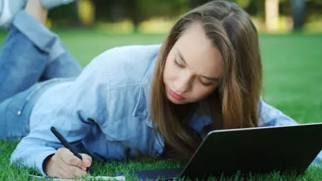 Estudiante Mujer Escribiendo En Un Cuaderno Desde Una Computadora Portátil En El Campus Universitario