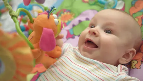 Primer Plano De La Cara De Niño Retrato De Un Bebé Feliz Sobre Una Alfombra Colorida Con Juguetes