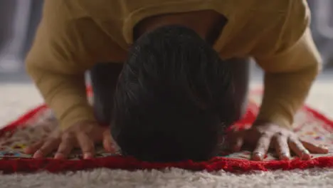 Muslim Man At Home Kneeling On Prayer Mat And Praying 2