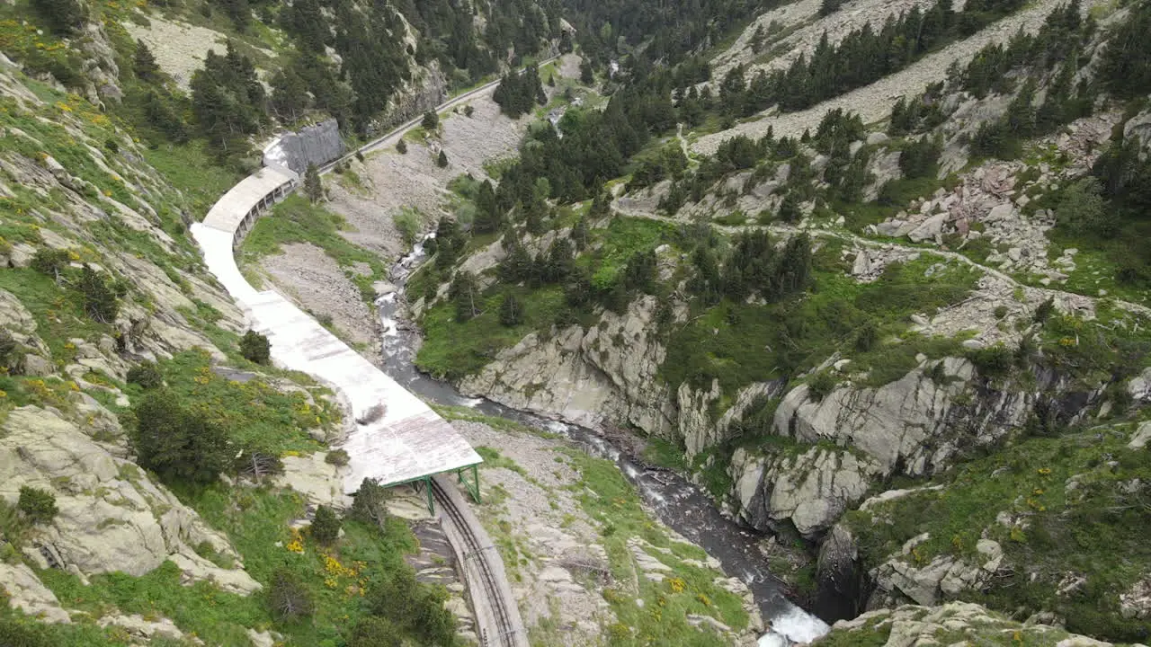 Toma Aérea De Un Paisaje Montañoso En El Que Las Vías Del Tren Corren A Lo Largo De Un Rico Río En Los Pirineos