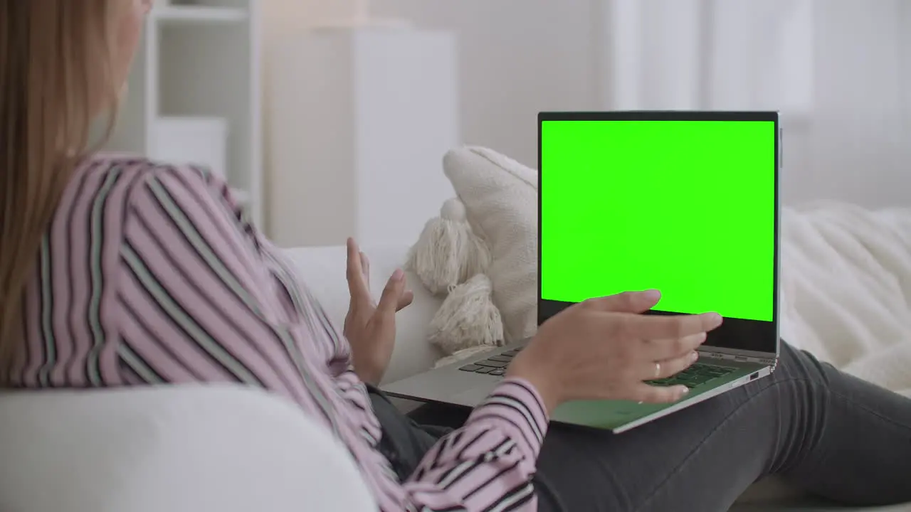 cheerful woman is using video call on laptop to communicate with friend green screen on notebook for chroma key technology