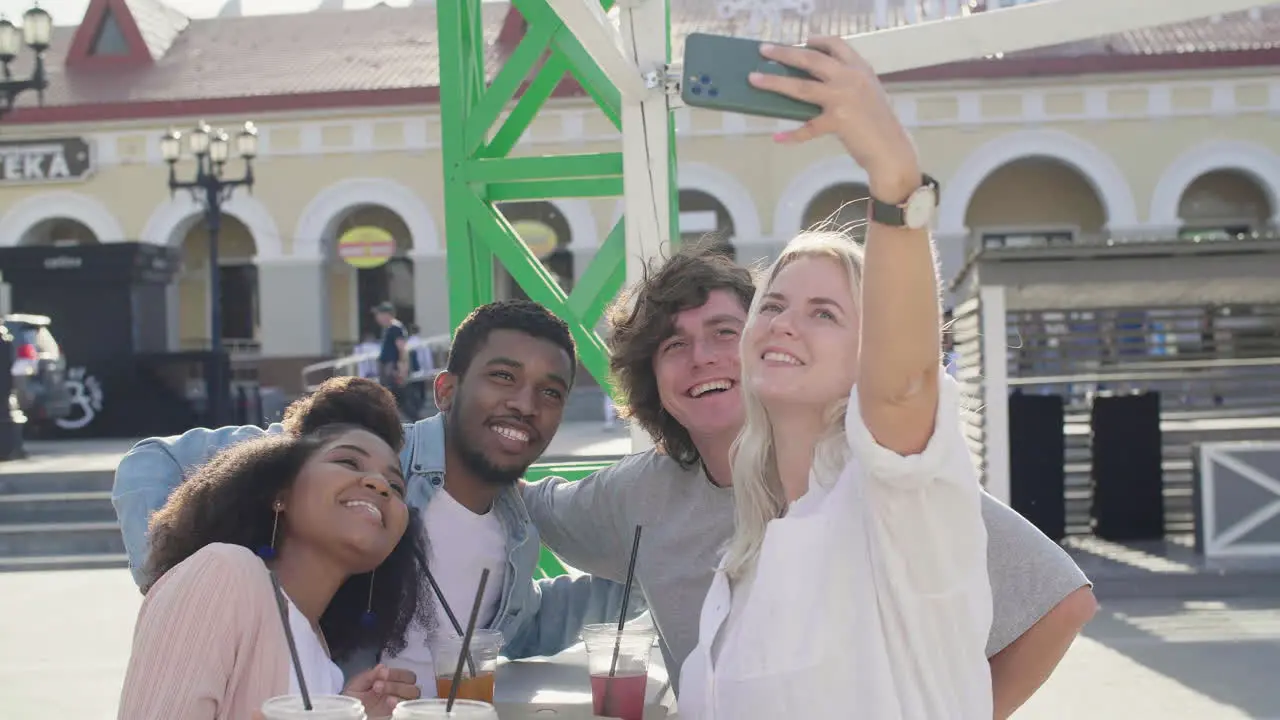 Group Of Cheerful Young Friends Taking Selfies And Having Fun Together While Standing At The Table And Eating Pizza In The Street