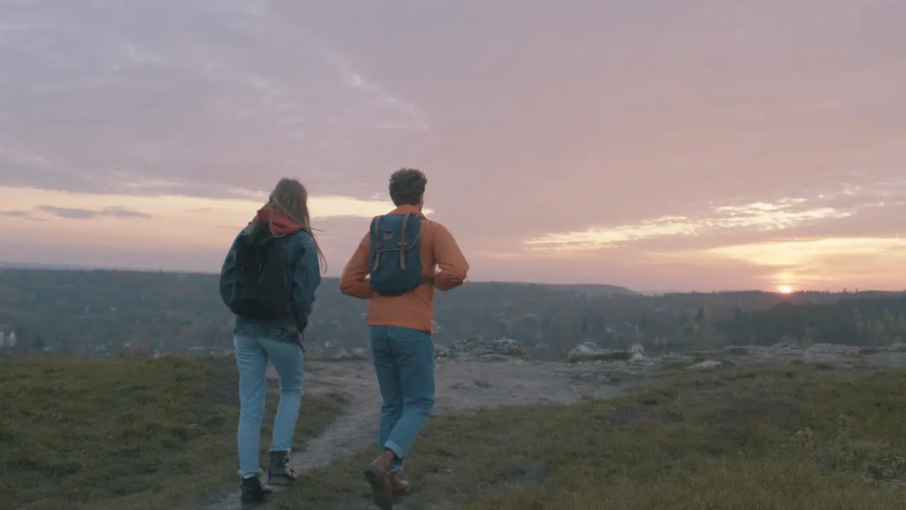  Beautiful sunset Young couple of female and male hikers at the top of the mountain