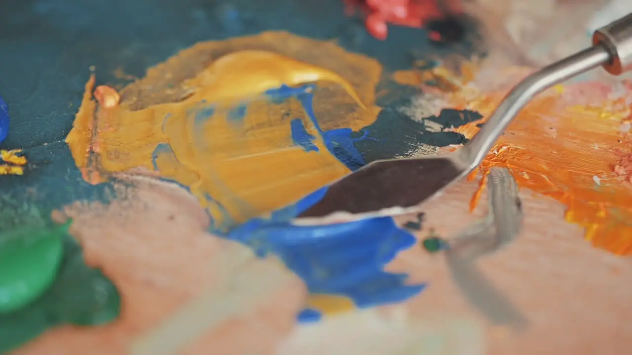 Detail Of A Spatula Mixing Colors On A Painter's Palette