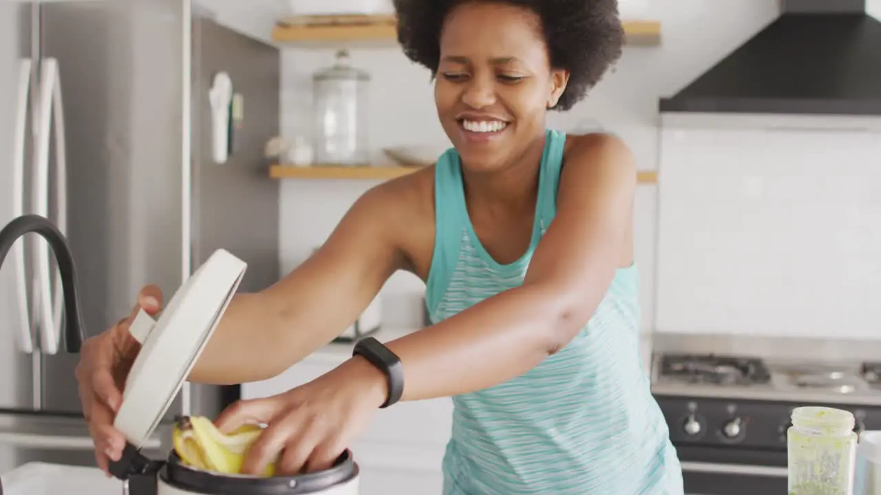 Happy african american woman cleaning throwing away waste in kitchen