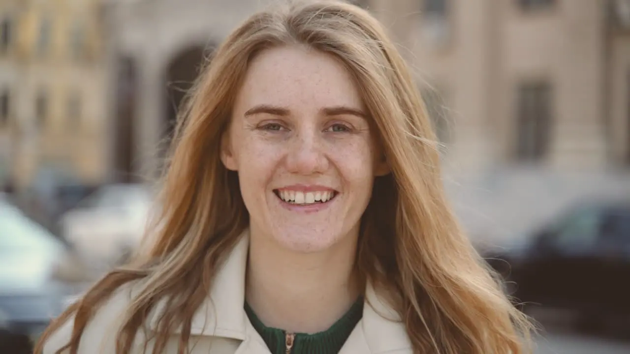 Red Haired Young Woman With Freckles Looks Smiling Directly Into The Camera