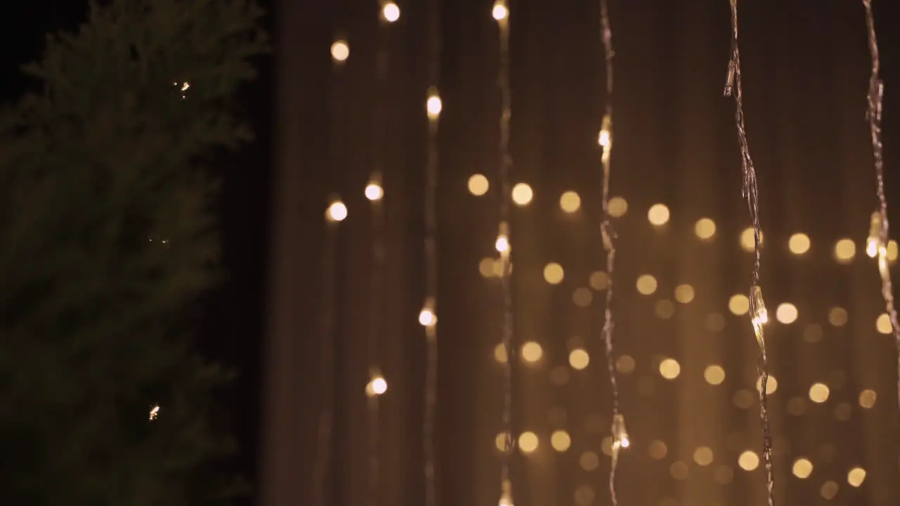 Camera Focuses On Garlands Of Golden Christmas Lights In Dark Party Room Decorated With Christmas Tree 3