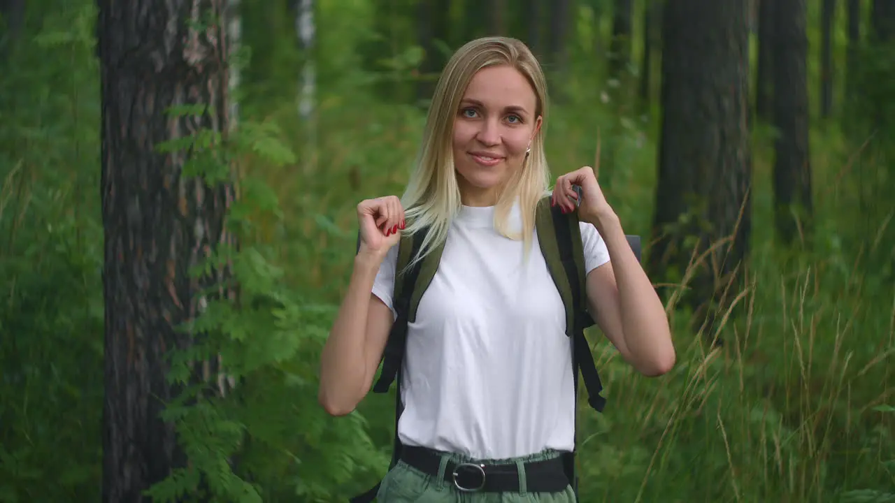 Atmospheric close-up portrait of young beautiful smiling girl in hat with flying hair at forest slow motion