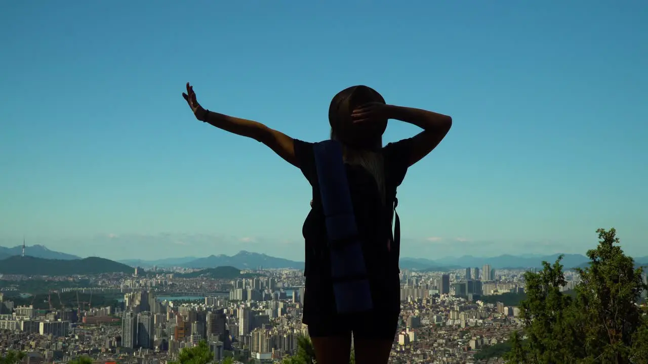 Back View Of A Woman Stretching Her Arms At The Peak Of Gwanaksan Mountain In South Korea Overlooking The Famous Seocho-gu District medium shot