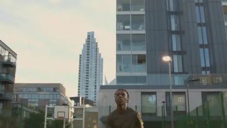 Male Football Player Heading Ball On Artificial Soccer Pitch In Urban City Area 1