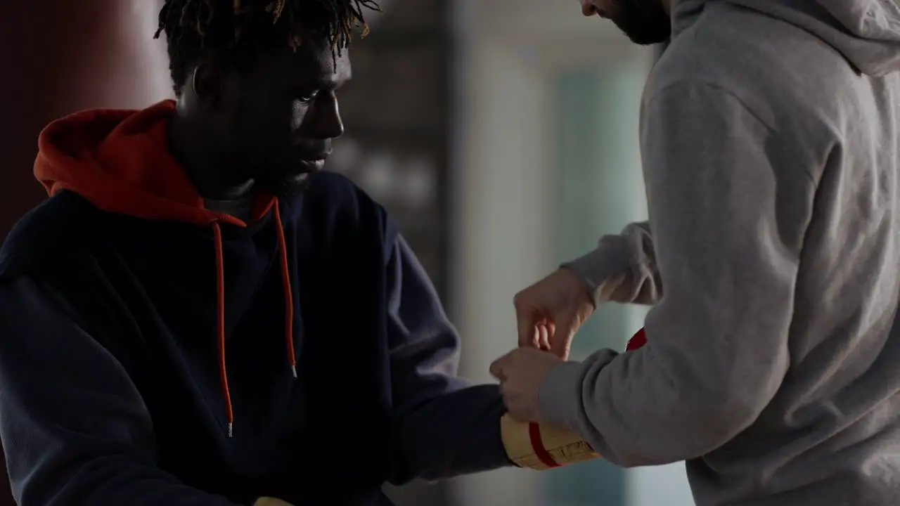 Assistant Helping To Put On Boxing Gloves To A Male Athlete Tie A Lace Close Up