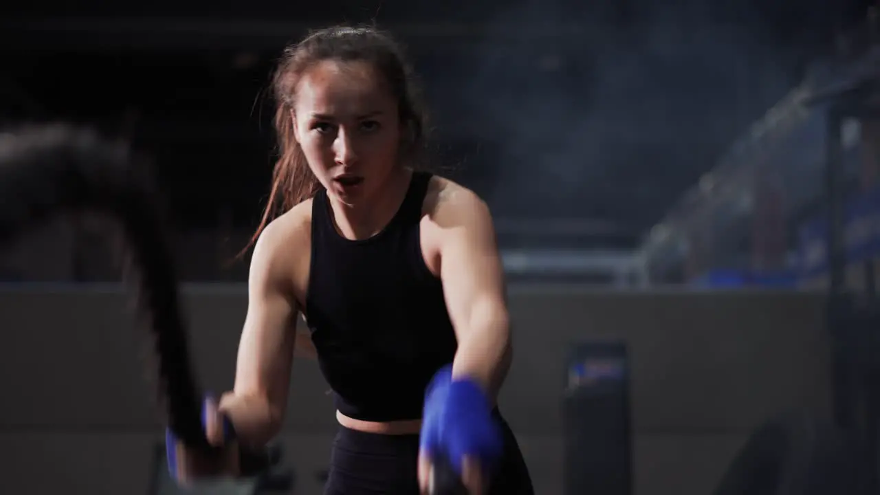 Young Woman Doing Some Crossfit Exercises With A Rope Indoor Front View