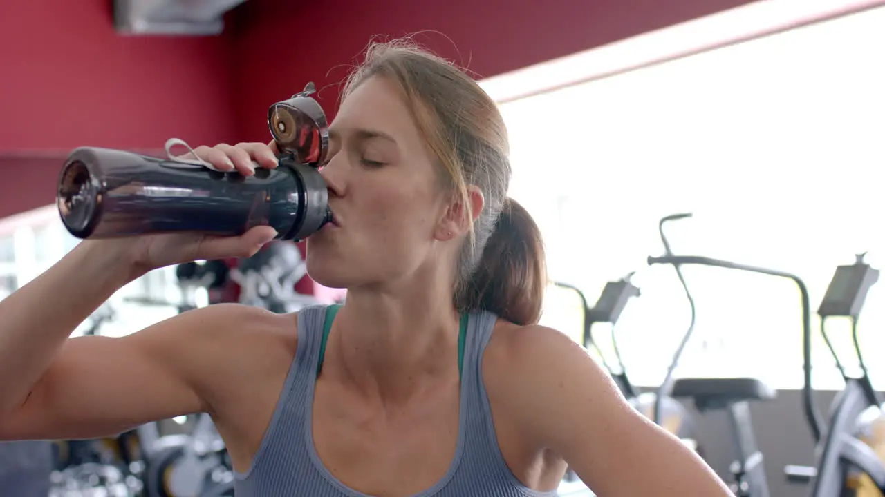 Fit young Caucasian woman hydrates during a gym workout