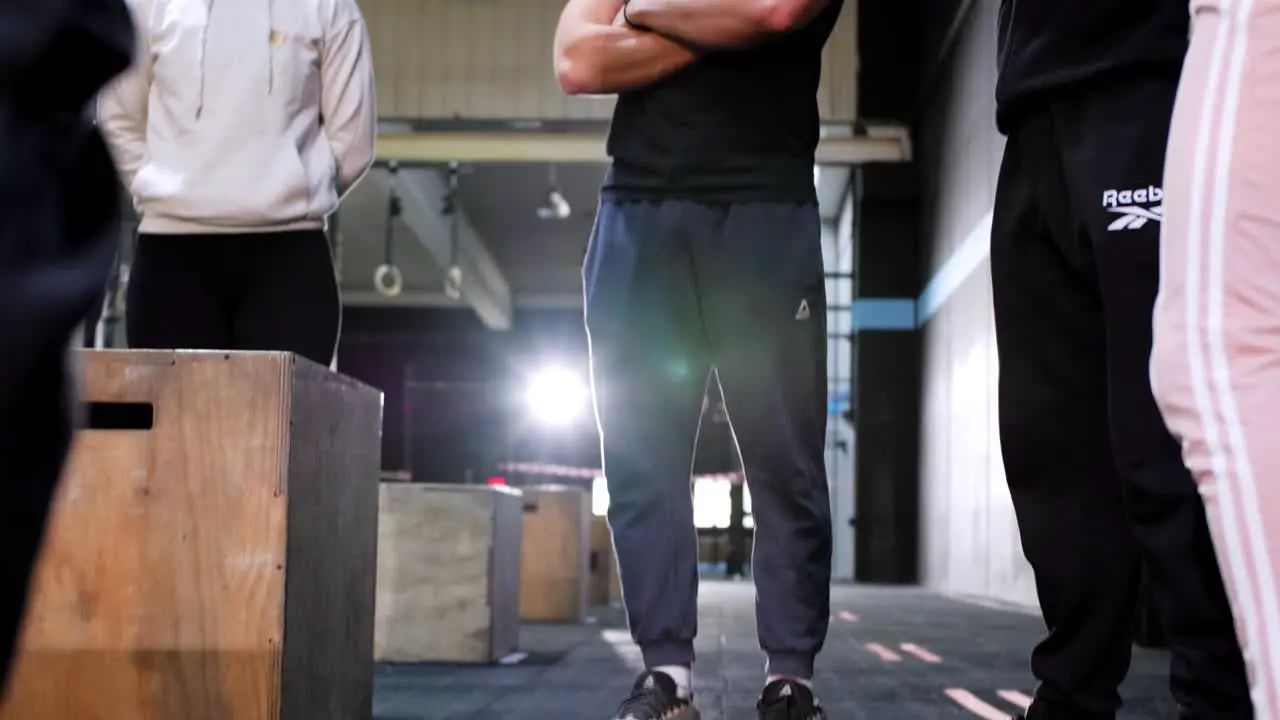 CrossFit Coaches Holding a Meeting in a Gym Prior to a Competition Bathed in Beautiful Lighting caméra tilt